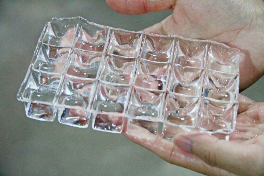 two hands holding square cube ice