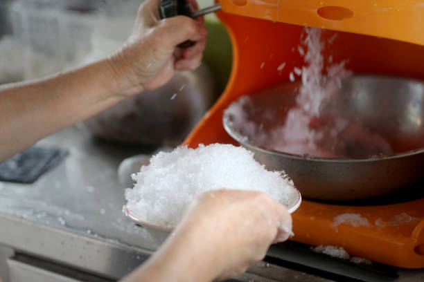A senior lady preparing shaved ice into a bowl.